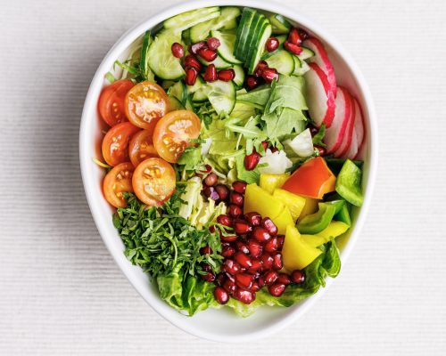 "A colorful bowl of fresh salad with various vegetables, topped with a light dressing."